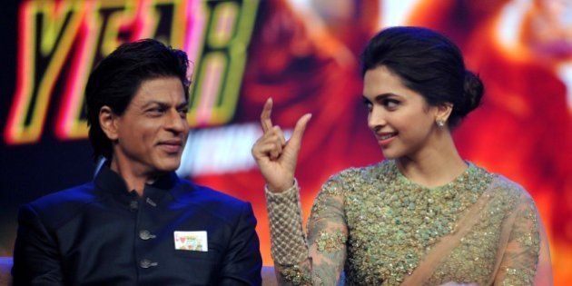 Indian Bollywood actors Shah Rukh Khan (L) and Deepika Padukone talk onstage during a promotional event for the forthcoming Hindi film 'Happy New Year' directed by Farah Khan and produced by Gauri Khan with music directtion by Vishal & Shekhar in Mumbai on late September 15, 2014. AFP PHOTO/STR (Photo credit should read STRDEL/AFP/Getty Images)