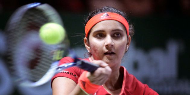 Sania Mirza of India makes a forehand return as she and partner Martina Hingis of Switzerland play Timea Babos of Hungary and Kristina Mladenovic of France during their doubles match at the WTA tennis finals in Singapore on Friday, Oct. 30, 2015. (AP Photo/Joseph Nair)