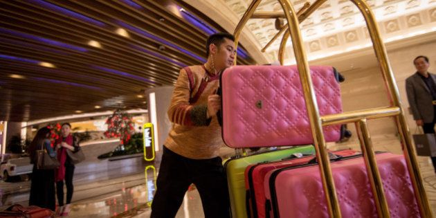 A porter loads a suitcase onto a trolley in the lobby of the Galaxy Macau casino resort, operated by Galaxy Entertainment Group Ltd., in Macau, China, on Monday, Mar. 16, 2015. Galaxy, the Macau casino operator that made Lui Che-woo Asia's second-richest person, is scheduled to report earnings on March 19. Photographer: Billy H.C. Kwok/Bloomberg via Getty Images