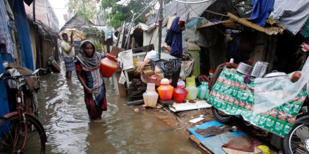 An Indian woman carries a vessel of water at a slum dwelling as it rains in Chennai, India, Friday, Nov. 13, 2015. Heavy rains lashed Chennai and other parts of Tamil Nadu state Friday, throwing life out of gear and disrupting train and flight schedules even as dozens were killed in rain related incidents, according to news reports. The Indian Meteorological Department has warned of more rains over the weekend. (AP Photo/Arun Sankar K)