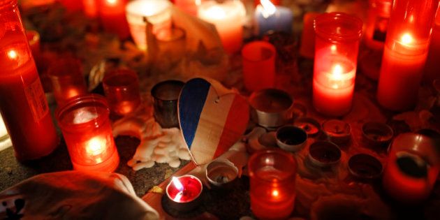 A wooden heart with the colours of the French flag rests among candles placed by people outside the French embassy in Madrid, Monday, Nov. 16, 2015. France is urging its European partners to move swiftly to boost intelligence sharing, fight arms trafficking and terror financing, and strengthen border security in the wake of the Paris attacks. (AP Photo/Francisco Seco)