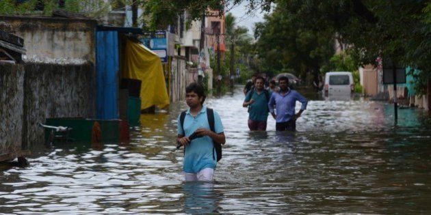 Indian people make their way on a flooded street following heavy rain in Chennai on November 16, 2015. Large areas of the southern Indian city of Chennai have been flooded following days of heavy rain. AFP PHOTO (Photo credit should read STR/AFP/Getty Images)