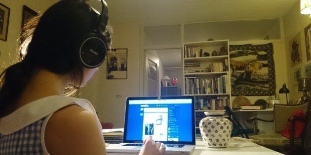Girl with headphone checks her social media on her laptop