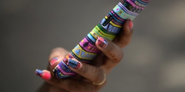 An Indian student checks her mobile phone in Mumbai on May 1, 2015. India raised a record USD17.6 billion during intense bidding on a government auction of wireless spectrum recently in one of the world's largest smartphone markets. The new spectrums for traditional voice and faster data services are seen as crucial for companies competing in the cut-throat Indian market, which has around 952 million mobile subscribers, according to figures released by India's telecoms regulator, TRAI. AFP PHOTO/ Indranil MUKHERJEE (Photo credit should read INDRANIL MUKHERJEE/AFP/Getty Images)