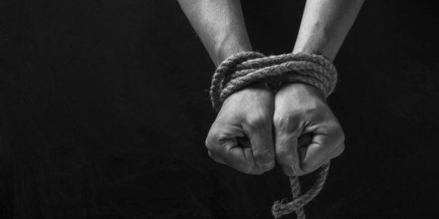 Hands tied with rope on a black background.