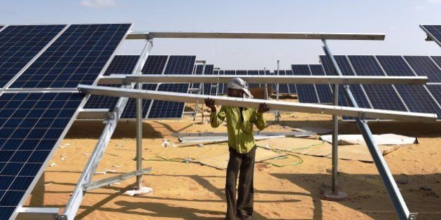 TO GO WITH: Climate-warming-COP21-India-energy-solar, FOCUS by Annie BanerjiIn this photograph taken on August 23, 2015, an Indian engineer fixes a solar panel into position at the under construction Roha Dyechem solar plant at Bhadla some 225 kms north of Jodhpur in the western Indian state of Rajasthan. Under a blistering sun, workers install a sea of solar panels in a north Indian desert as part of the government's clean energy push --- and its trump card at upcoming climate change talks in Paris. AFP PHOTO/MONEY SHARMA (Photo credit should read MONEY SHARMA/AFP/Getty Images)