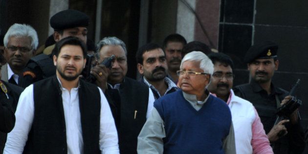 Indian politician Lalu Prasad Yadav (R) walks with his son Tejaswi (L) and security personnel as he leaves Birsa Munda Central Jail in Ranchi on December 16, 2013, following his release from the prison. Yadav, the head of the Rashtriya Janata Dal (RJD) party has been released some two-and-a-half months after he was convicted in a fodder scam case. AFP PHOTO/STR (Photo credit should read STRDEL/AFP/Getty Images)