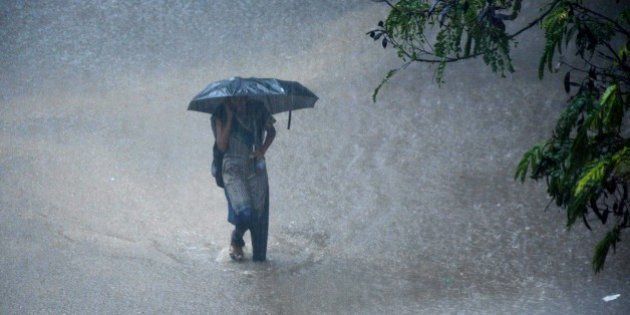 A young Indian woman walks under an umbrella through floodwaters in Chennai on December 1, 2015, during a downpour of heavy rain in the southern Indian city. Heavy rains pounded several parts of the southern Indian state of Tamil Nadu and inundating most areas of Chennai, severely disrupting flights, train and bus services and forcing the postponment of half-yearly school exams. AFP PHOTO/STR / AFP / STRDEL (Photo credit should read STRDEL/AFP/Getty Images)