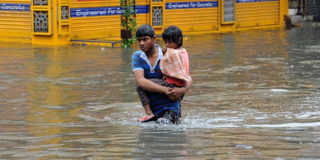 A boy carries a child and wades through a flooded street in Chennai, in the southern Indian state of Tamil Nadu, Wednesday, Dec. 2, 2015. Weeks of torrential rains have forced the airport in the state capital Chennai to close and have cut off several roads and highways, leaving tens of thousands of people stranded in their homes, government officials said Wednesday. (AP Photo)