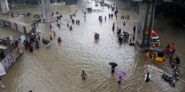 People wade through a flooded road in Chennai, Tamil Nadu, India, Wednesday, Dec. 2, 2015. Weeks of torrential rains have forced the Chennai airport in southern India to close and have cut off several roads and highways, leaving tens of thousands of people stranded in their homes, government officials said Wednesday. (AP Photo)