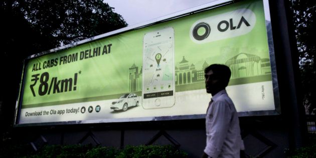 A pedestrian walks past an advertisement for the Ola ride-hailing service and application, owned by ANI Technologies Pvt., in New Delhi, India, on Saturday, Sept. 19, 2015. Ola, the operator of an Indian taxi-hailing app, will lease cars to boost the number of vehicles in its network to stave off competition from Uber Technologies Inc. Photographer: Dhiraj Singh/Bloomberg via Getty Images