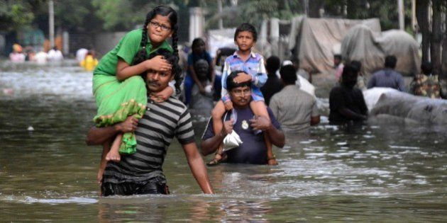 Indian residents carry children as they walk through floodwaters in Chennai on December 3, 2015. Thousands of rescuers raced to evacuate residents from deadly flooding, as India's Prime Minister Narendra Modi went to the southern state of Tamil Nadu to survey the devastation. More than 40,000 people have been rescued in recent days after record rains lashed the coastal state, worsening weeks of flooding that has killed 269 people AFP PHOTO/STR / AFP / STRDEL (Photo credit should read STRDEL/AFP/Getty Images)