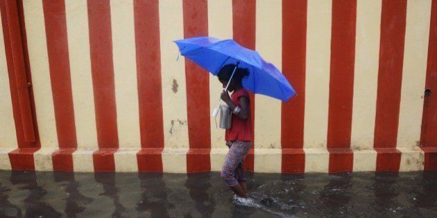 An Indian girl walks under an umbrella along a waterlogged street following heavy rain in Chennai on November 13, 2015. AFP PHOTO / STR (Photo credit should read STRDEL/AFP/Getty Images)