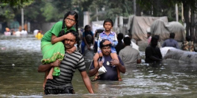 Indian residents carry children as they walk through floodwaters in Chennai on December 3, 2015. Thousands of rescuers raced to evacuate residents from deadly flooding, as India's Prime Minister Narendra Modi went to the southern state of Tamil Nadu to survey the devastation. More than 40,000 people have been rescued in recent days after record rains lashed the coastal state, worsening weeks of flooding that has killed 269 people AFP PHOTO/STR / AFP / STRDEL (Photo credit should read STRDEL/AFP/Getty Images)