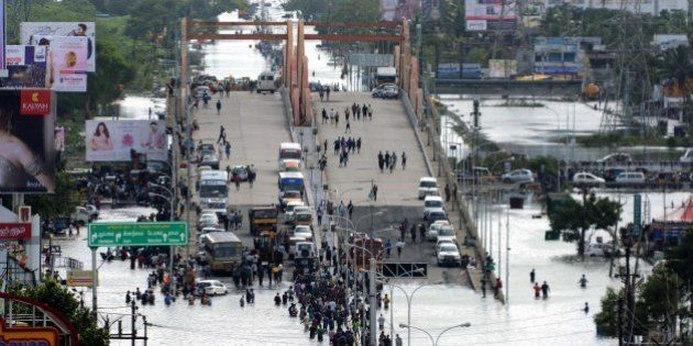 Indian residents and motorists gather on a flyover as others wade through floodwaters in Chennai on December 3, 2015. Thousands of rescuers raced to evacuate residents from deadly flooding, as India's Prime Minister Narendra Modi went to the southern state of Tamil Nadu to survey the devastation. More than 40,000 people have been rescued in recent days after record rains lashed the coastal state, worsening weeks of flooding that has killed 269 people AFP PHOTO/STR / AFP / STRDEL (Photo credit should read STRDEL/AFP/Getty Images)