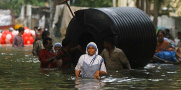 People use a water tank for floatation as they wade through flood waters in Chennai, India, Thursday, Dec. 3, 2015. The heaviest rainfall in more than 100 years has devastated swathes of the southern Indian state of Tamil Nadu, with thousands forced to leave their submerged homes and schools, offices and a regional airport shut for a second day Thursday.( AP Photo)
