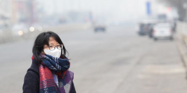 BEIJING, CHINA - DECEMBER 07: (CHINA OUT) A woman wearing mask walks along a road in heavy smog on December 7, 2015 in Beijing, China. China's National Meteorological Center (NMC) issued a yellow alert on Sunday as heavy smog will cover the country's northern regions in the following two days. (Photo by ChinaFotoPress/ChinaFotoPress via Getty Images)