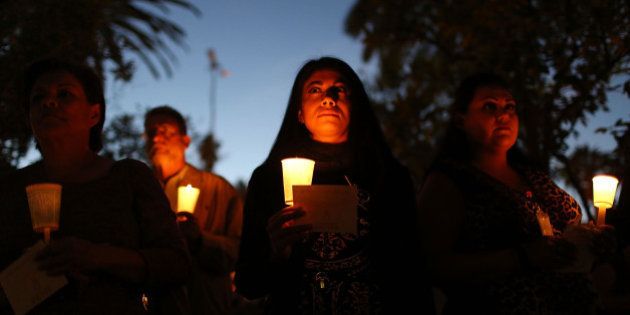 SAN BERNARDINO, CA - DECEMBER 07: People hold candles as they attend a vigil held at the San Bernardino County Board of Supervisors headquarters to remember those injured and killed during the shooting at the Inland Regional Center on December 7, 2015 in San Bernardino, California. FBI and other law enforcement officials continue to investigate the mass shooting that left 14 people dead and another 21 injured on December 2nd. (Photo by Joe Raedle/Getty Images)