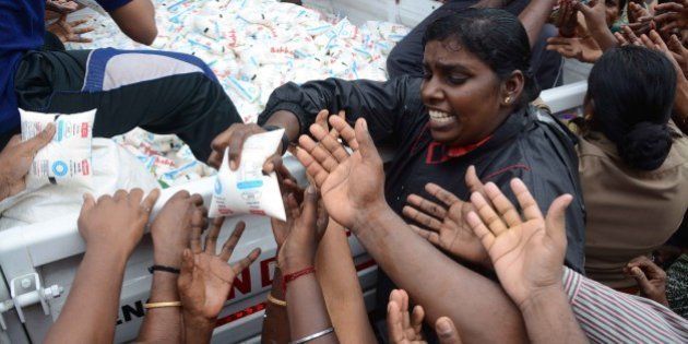 Indian volunteers distribute packets of milk from the back of a vehicle to flood affected residents in Chennai on December 5, 2015. Thousands of rescuers are racing to evacuate victims of the Tamil Nadu flooding, which has claimed nearly 300 lives since November 9. Weather officials said rainfall in Chennai had diminished since earlier in the week, but parts of the city of 4.6 million people remained submerged. AFP PHOTO/STR / AFP / STRDEL (Photo credit should read STRDEL/AFP/Getty Images)