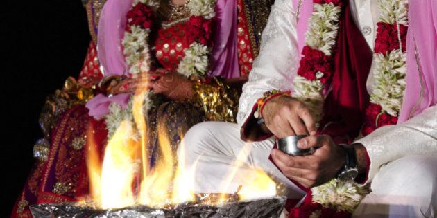 An Indian couple worshipping the fire deity, as a part of the Indian traditional wedding rituals.Fire deity is considered to be a primary witness of a Hindu marriage.