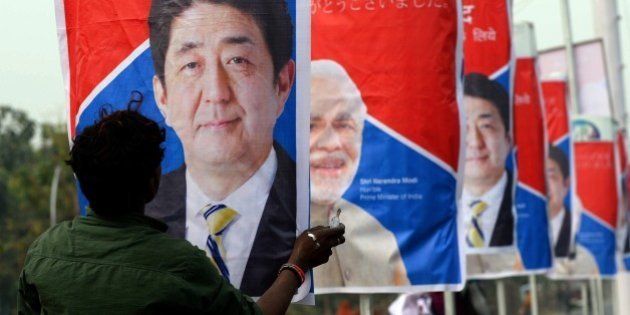 An Indian worker hangs posters of Japan's Prime Minister Shinzo Abe (L) and India's Prime Minister Narendra Modi (R) along a road in Varanasi on December 11, 2015. Japanese Prime Minister Shinzo Abe will look to seal a deal on building India's first bullet train after he arrived in New Delhi on December 11, for talks with counterpart and conservative soulmate Narendra Modi. Abe will meet Indian business leaders in the capital before taking a tour with Modi on December 12, of India's holiest city of Varanasi and the prime minister's parliamentary constituency. AFP PHOTO/PRAKASH SINGH / AFP / PRAKASH SINGH (Photo credit should read PRAKASH SINGH/AFP/Getty Images)