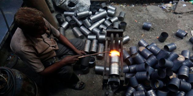 A worker uses a blowtorch to add texture to stainless steel containers inside a manufacturing workshop in the suburb of Mira-Bhayander in Thane, Maharashtra, India, on Tuesday, Jan. 7, 2014. Tata Steel Ltd. and Steel Authority of India Ltd., the nations biggest producers, are set to report their smallest profit margins in more than a decade as demand increases at the slowest pace since the global recession. Photographer: Vivek Prakash/Bloomberg via Getty Images