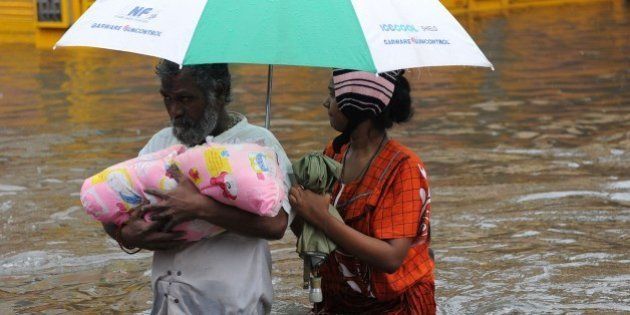 An Indian family wade through floodwaters in Chennai on December 2, 2015. India has deployed troops to Tamil Nadu and closed the main airport there after heavy rains worsened weeks of flooding that has killed nearly 200 people in the southern coastal state. Thousands of rescuers carrying diving equipment, inflatable boats and medical equipment were battling to evacuate victims across the flooded state, officials said. AFP PHOTO/STR / AFP / STRDEL (Photo credit should read STRDEL/AFP/Getty Images)