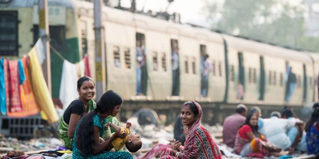 KOLKATA, INDIA - DECEMBER 12: Women take care of a baby in a slum on the railway tracks as a commuter train goes past on December 12, 2013 in Kolkata, India. Almost one third of the Kolkata population live in slums and a further 70,000 are homeless. (Photo by Samir Hussein/Getty Images)