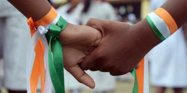 Indian school student hold hands, decorated with the national colours, as they wait to perform during celebrations of India's 68th Independence Day at school in Kolkata on August 15, 2014. India celebrates its anniversary of independence from Britain on August 15 with great pomp and with the Indian tricolour hoisted atop schools, government offices prominent buildings and homes. AFP PHOTO/Dibyangshu Sarkar (Photo credit should read DIBYANGSHU SARKAR/AFP/Getty Images)