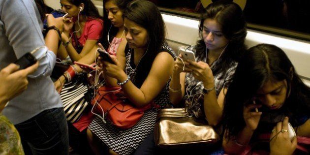 Indian women use their smartphones as they travel in the metro carriage reserved for women in New Delhi on July 14, 2015. With the first stretch of metro inaugurated in the city in 2002, as of June 2015 the network consists of five regular lines and one express line covering 193 kms and 140 stations. AFP PHOTO/ Anna ZIEMINSKI (Photo credit should read ANNA ZIEMINSKI/AFP/Getty Images)