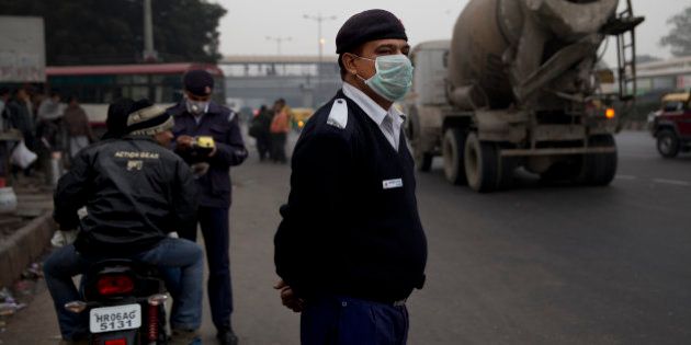 An Indian traffic policeman wears a mask as he stands on a road in New Delhi, India, Wednesday, Jan. 6, 2016. The Indian capital is currently testing a formula to reduce its record-high air pollution by limiting the numbers of cars on the streets for two weeks.(AP Photo /Tsering Topgyal)