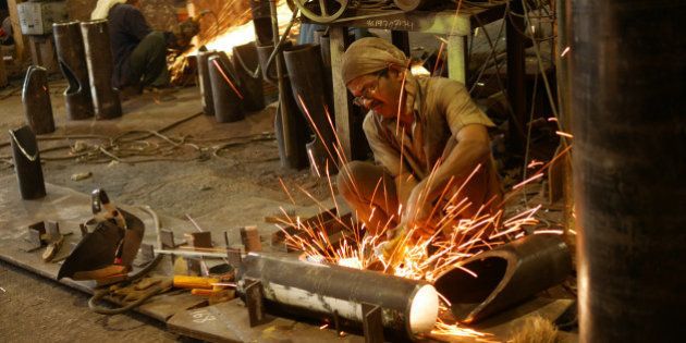 Men working with an angle grinder as it sprays sparks inside a metalworking factory in the docks are of Mumbai.