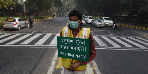 NEW DELHI, INDIA - JANUARY 4: A volunteer holds a placard for pollution free capital at APJ Kalam crossing during the Delhi's odd-even traffic arrangements on January 4, 2016 in New Delhi, India. Contrary to apprehensions, Delhi's odd-even vehicle scheme aimed at battling pollution did not lead to the feared problems on Monday, the first full working day of the New Year. The 15-day odd-even scheme started on January 1 and aims to put odd numbered vehicles on the roads on odd dates and even numbered vehicles on even dates. (Photo by Vipin Kumar/Hindustan Times via Getty Images)