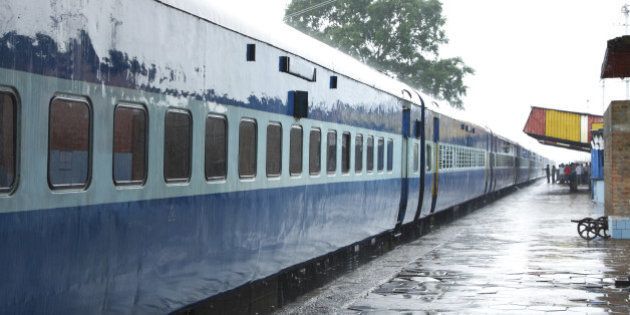 blue color coaches of indian train stainding in a station during rain