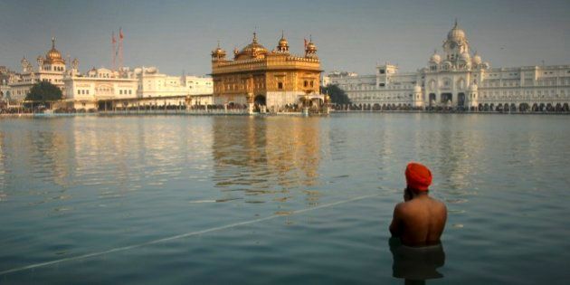 An Indian Sikh devotee takes a holy dip in the sacred pond at the Golden Temple in Amritsar, India, Wednesday, Jan. 1, 2014. Thousands of Sikh devotees stand in a queue to pay obeisance at the Golden Temple, Sikhs' holiest shrine, on the first day of the New Year. (AP Photo/Sanjeev Syal)