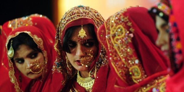 Pakistani brides talk as they attend a mass-wedding ceremony in Karachi on late March 24, 2014. Some 115 couples participated in the mass-wedding ceremony organised by a local charity welfare trust. AFP PHOTO / ASIF HASSAN (Photo credit should read ASIF HASSAN/AFP/Getty Images)