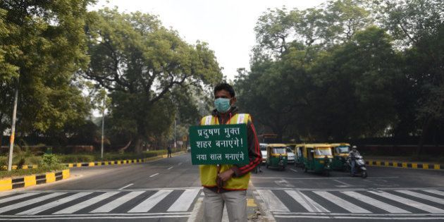 NEW DELHI, INDIA - JANUARY 4: A volunteer holds a placard for pollution free capital at APJ Kalam crossing during the Delhi's odd-even traffic arrangements on January 4, 2016 in New Delhi, India. Contrary to apprehensions, Delhi's odd-even vehicle scheme aimed at battling pollution did not lead to the feared problems on Monday, the first full working day of the New Year. The 15-day odd-even scheme started on January 1 and aims to put odd numbered vehicles on the roads on odd dates and even numbered vehicles on even dates. (Photo by Vipin Kumar/Hindustan Times via Getty Images)