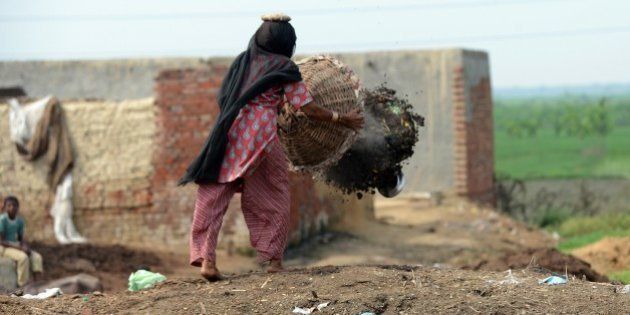 TO GO WITH AFP STORY 'INDIA-HEALTH-POVERTY-SEWAGE-SCAVENGERS' by Adam PlowrightIn this picture taken on August 10, 2012, 60 year old manual scavenger Kela dumping a basket of human excrement after cleaning toilets in Nekpur village, Muradnagar in Uttar Pradesh, some 40 kms east of New Delhi. Already illegal under a largely ineffective 1993 law, the government has promised to have another go at stamping out the practice with new legislation set to come up in the last parliament session of the year, which opens this week. AFP PHOTO/ Prakash SINGH (Photo credit should read PRAKASH SINGH/AFP/Getty Images)