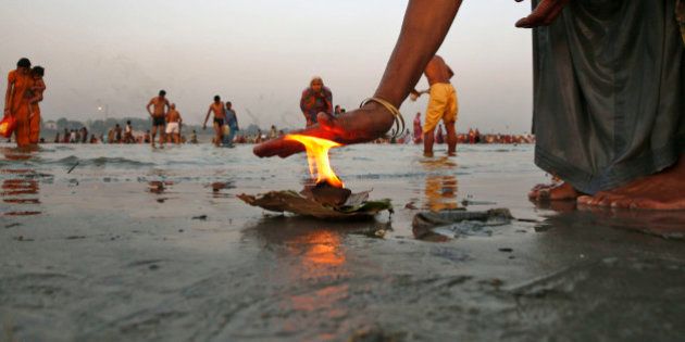 An Indian Hindu devotee offers prayers with a lamp, as others take holy dips at Sangam, the confluence of the Rivers Ganges, Yamuna and the mythical Saraswati, in Allahabad, India, Thursday, May 28, 2015. Hindus across the country are celebrating Ganga Dussehra, devoted to the worship of the River Ganges. (AP Photo/Rajesh Kumar Singh)