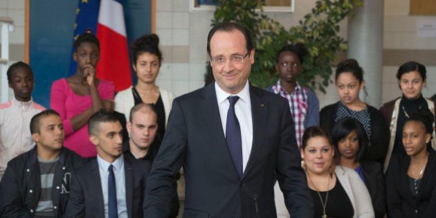 France's President Francois Holland acknowledges teachers and pupils prior to his speech at a school in Les Mureaux, a poor suburb of Paris, as part of a visit focused on the youth employment, Tuesday, April 30, 2013. Placard reads,