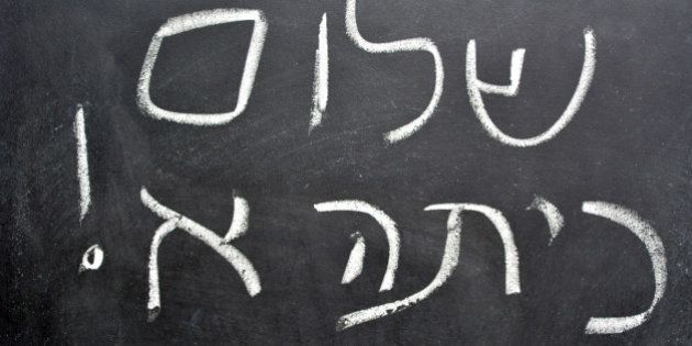 Hello First Grade greetings in Hebrew (Shalom Kita Alef) on a chalkboard in Israeli primary school at the beginning of the school year.Concept photo of early age education,learning ,studying, teaching