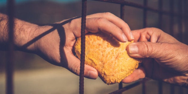 Person gives an immigrant a bread through the fence, border, hands only