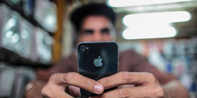 A man operates a Apple Inc. iPhone at a mobile phone store in this arranged photograph in Mumbai, India, on Saturday, Feb. 28, 2015. The government auction of telecom wireless spectrum starting March 4 is expected to raise as much as $15.6 billion from service providers including those controlled by billionaires Kumar Mangalam Birla, Sunil Mittal and Anil Ambani, according to ICRA Ltd. Photographer: Dhiraj Singh/Bloomberg via Getty Images