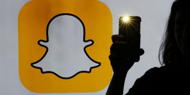 A woman takes a photograph with a camera whilst standing against an illuminated wall bearing Snapchat Inc.'s logo in this arranged photograph in London, U.K., on Tuesday, Jan. 5, 2016. Snapchat Inc. develops mobile communication applications that allows the user to send and receive photos, drawings, text, or videos that will only last for an allotted amount of time. Photographer: Chris Ratcliffe/Bloomberg via Getty Images
