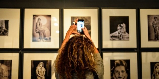 ---RESTRICTED TO EDITORIAL USE, MANDATORY MENTION OF THE ARTIST UPON PUBLICATION, TO ILLUSTRATE THE EVENT AS SPECIFIED IN THE CAPTION------ In this photograph taken on January 28, 2016 an Indian woman takes picture of the photographs of Maharanis by Poddar & Gaskell at the India Art Fair in New Delhi. For years, its been Indias grand art festival but this year more than ever, India Art Fair is raking more eyes balls by bringing a gamut of modern and contemporary works from across the world to satiate the growing art appetite of the metropolis - Delhi. AFP PHOTO / CHANDAN KHANNA / AFP / Chandan Khanna (Photo credit should read CHANDAN KHANNA/AFP/Getty Images)