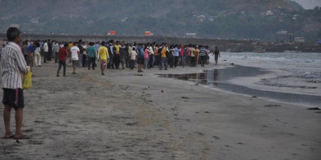 People gather on the beach after more than a dozen college students were swept away at Murud on the Arabian Sea coast about 150 kilometers (95 miles) south of Mumbai, Maharashtra state, India, Monday, Feb. 1, 2016. Police say the students who were on a school picnic have drowned while swimming in the sea in western India. (AP Photo/Sudhir Nazare)