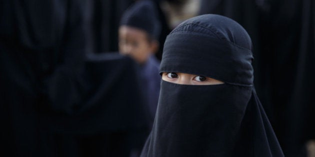 MAKASSAR, SOUTH SULAWESI, INDONESIA - SEPTEMBER 22: A girl from the Islamic commune An-Nadzir looks on as she attends Eid Al Adha mass prayer at Mawang Lake, Gowa Regency on September 22, 2015 in Makassar, Indonesia. An-Nadzir is an exclusive Islamic community of 5,000-10,000 followers across Indonesia, which has one of the worlds largest populations of Muslims.While the beliefs of Muslims in the An-Nadzir community are similar to mainstream Muslims, they observe different prayer times, men wear dark robes, and women wear full burqas. People live a basic life of farming and fishing in the remote Gowa district, and believe in salvation without discrimination and living in peace with others. Based on Rukyah (the observation on the appearance of a new moon) and hisab (astronomical calculations), the An Nadzir muslim community determined that Eid Al Adha 1436 would fall on Tuesday, two days earlier than the date set by the national government. (Photo by Agung Parameswara/Getty Images)