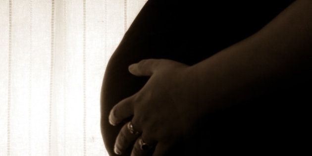 Sepia shot of a pregnant woman holding her belly.