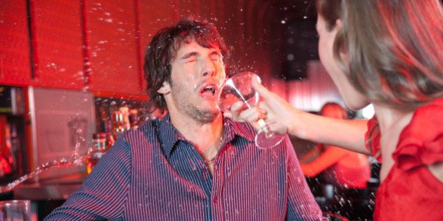 Woman in nightclub throwing beverage in man's face