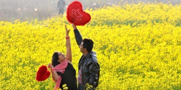 CHANDIGARH, INDIA - FEBRUARY 14: A young couple sharing a light moment in an open field on the outskirts of Chandigarh as they celebrated Valentine's Day, on February 14, 2015 in Chandigarh, India. Valentine's Day, also known as Saint Valentine's Day or the Feast of Saint Valentine, is a celebration observed on February 14 each year. It is celebrated in many countries around the world, although it is not a public holiday in most of them. (Photo by Keshav Singh/Hindustan Times via Getty Images)